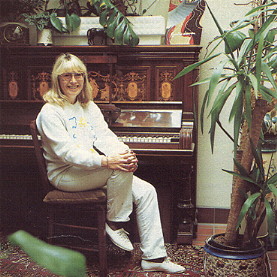 Cynthia sitting at the piano on which her son Julian composed his early hits